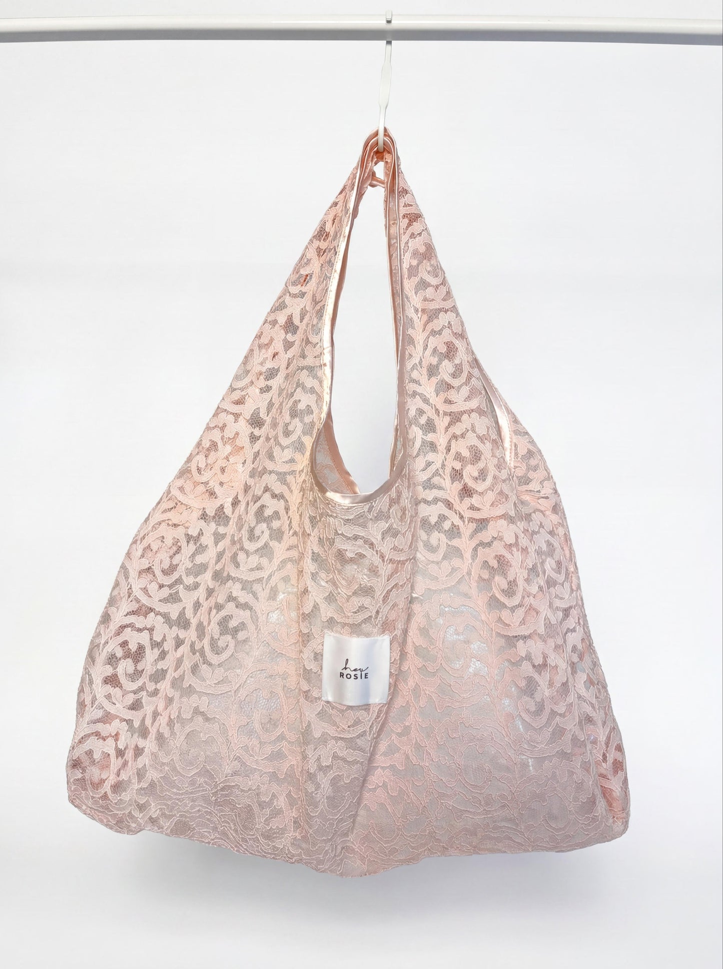 Pink lace bag with a visible brand label on a white background