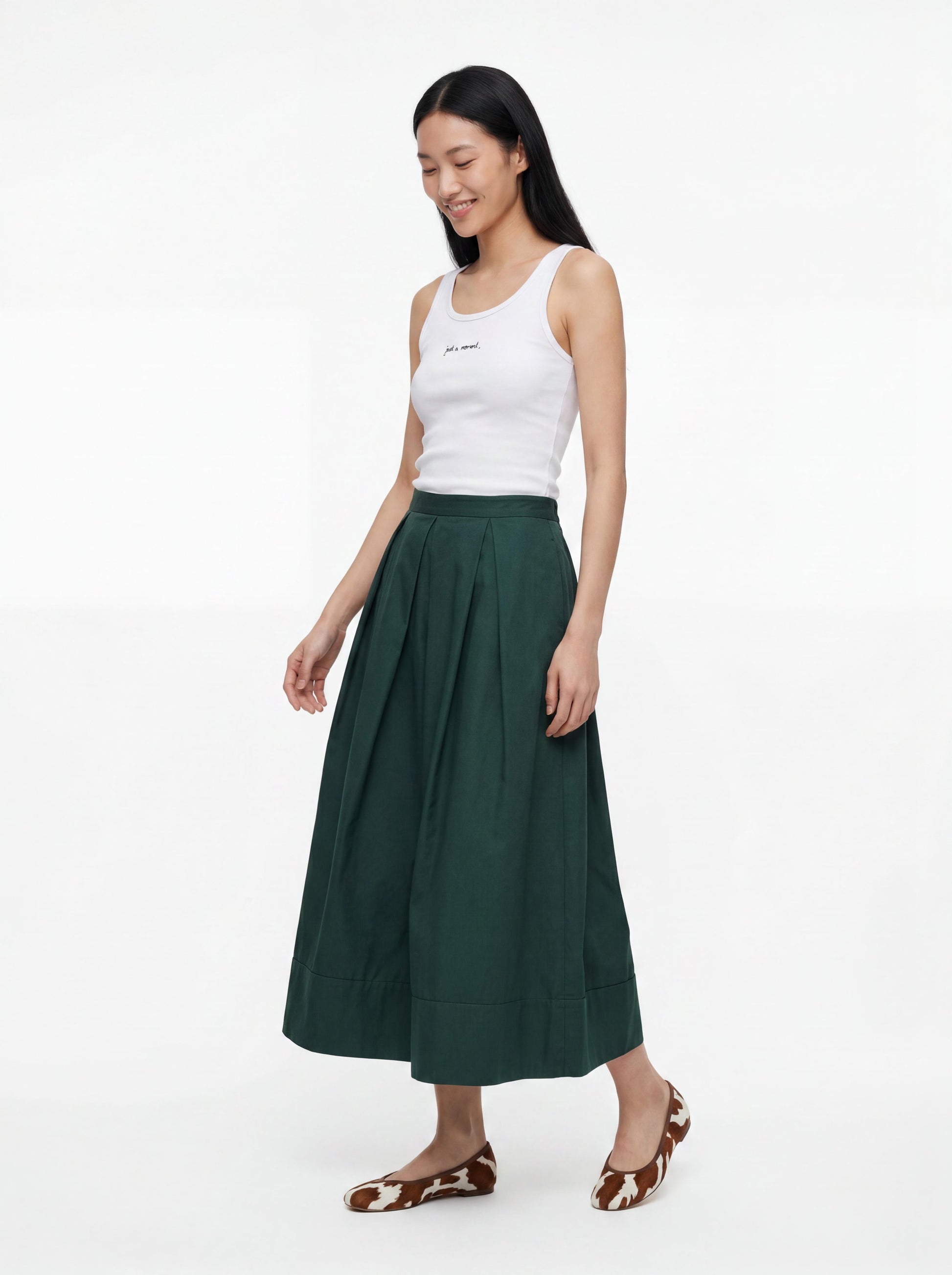 Woman wearing a white tank top and green skirt on a white background